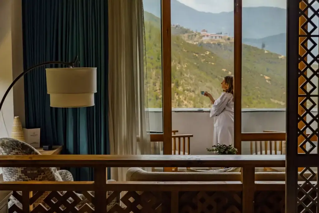 a woman standing in front of a window with a cup of coffee