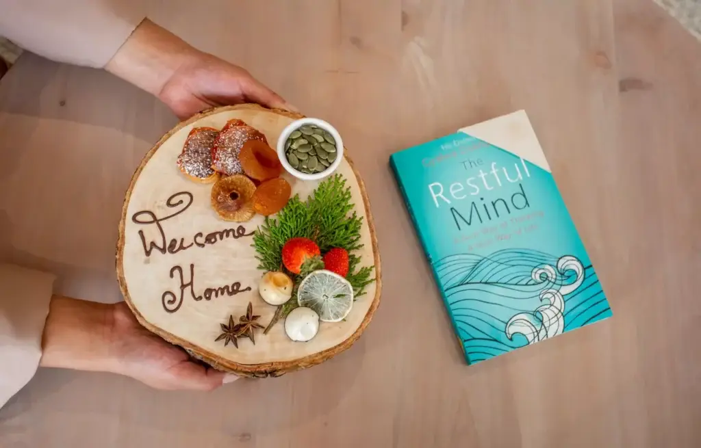 a person holding a piece of wood with food on it next to a book