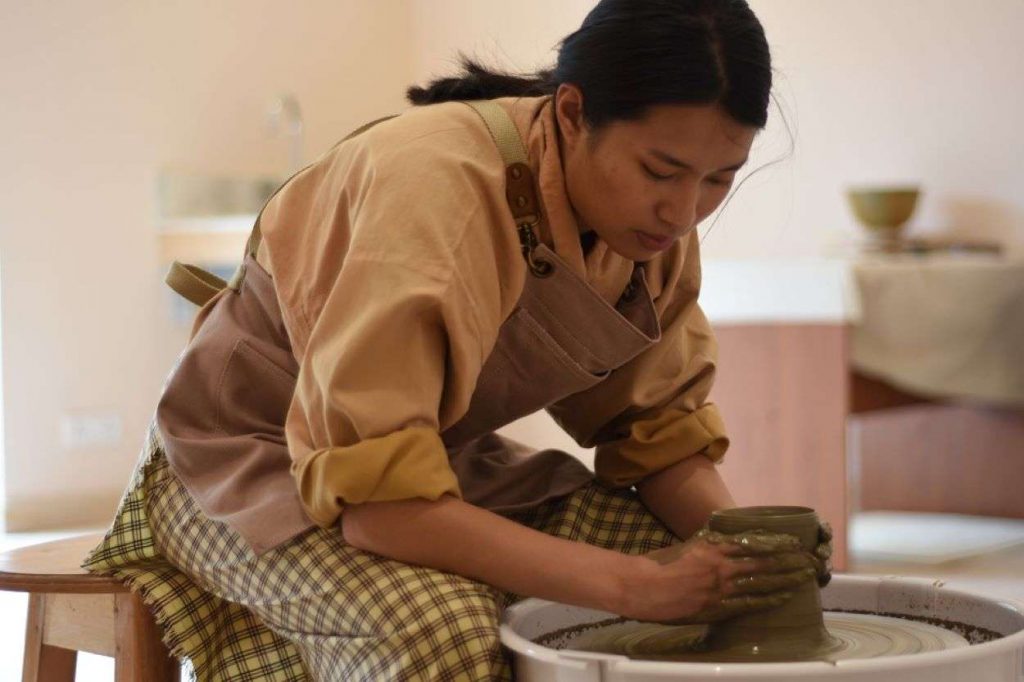 a woman working on a pottery wheel