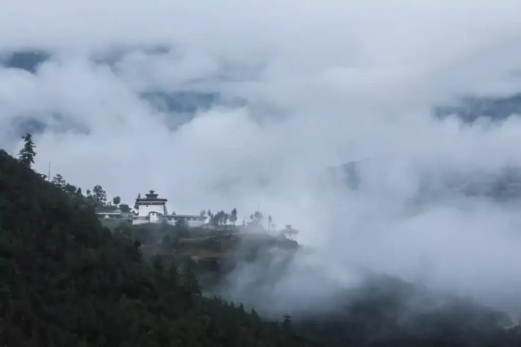 a building on a hill with clouds