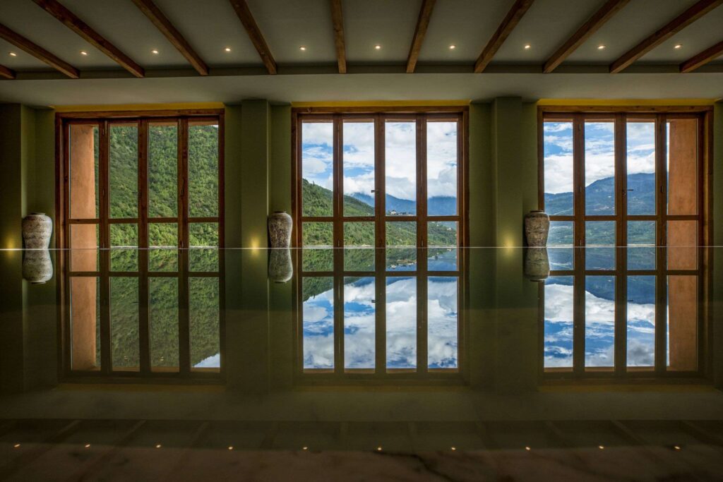 a large room with a pool large windows and a view of the mountains in bhutan spirit sanctuary