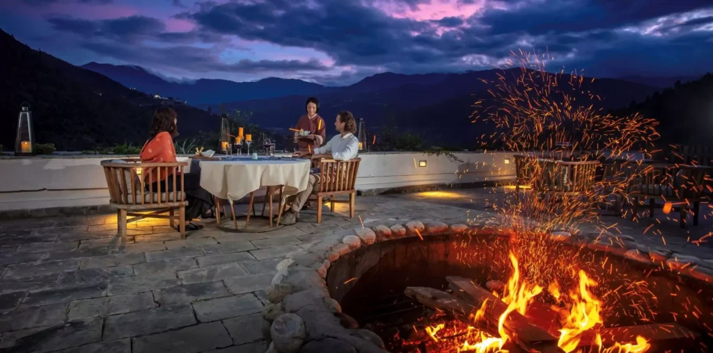 a couple sitting at a table with a fire in the background