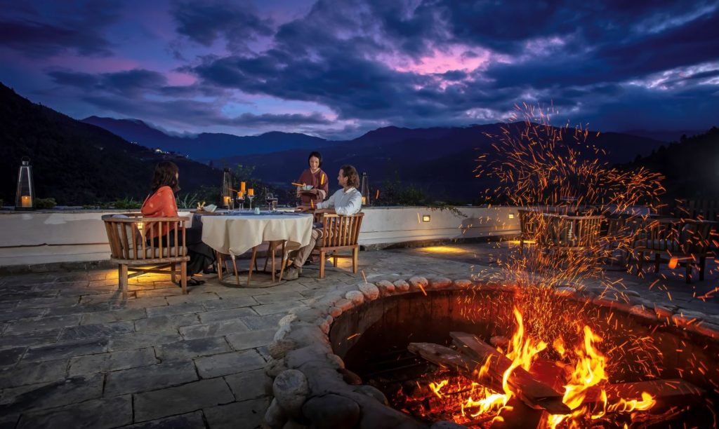 a couple sitting at a table with a fire in the background