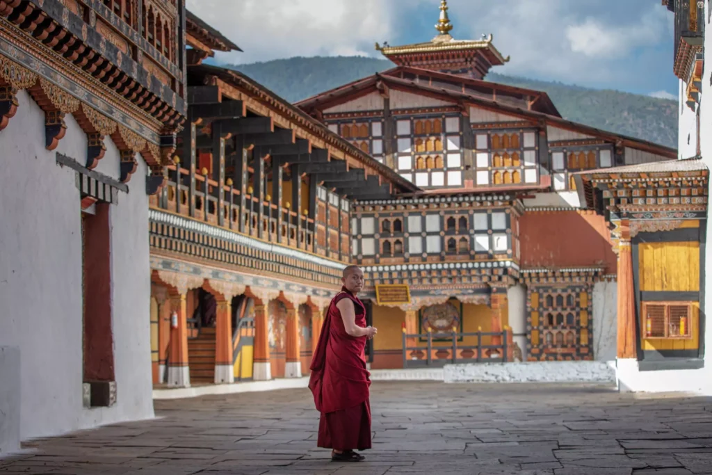 a monk in a red robe in front of a building