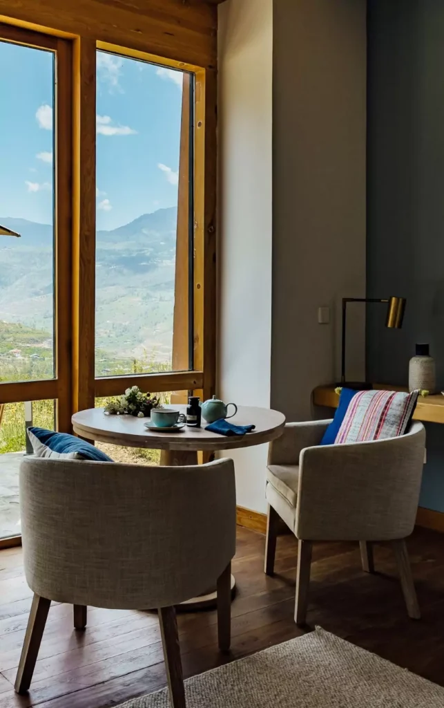a room with a table and chairs and a view of mountains