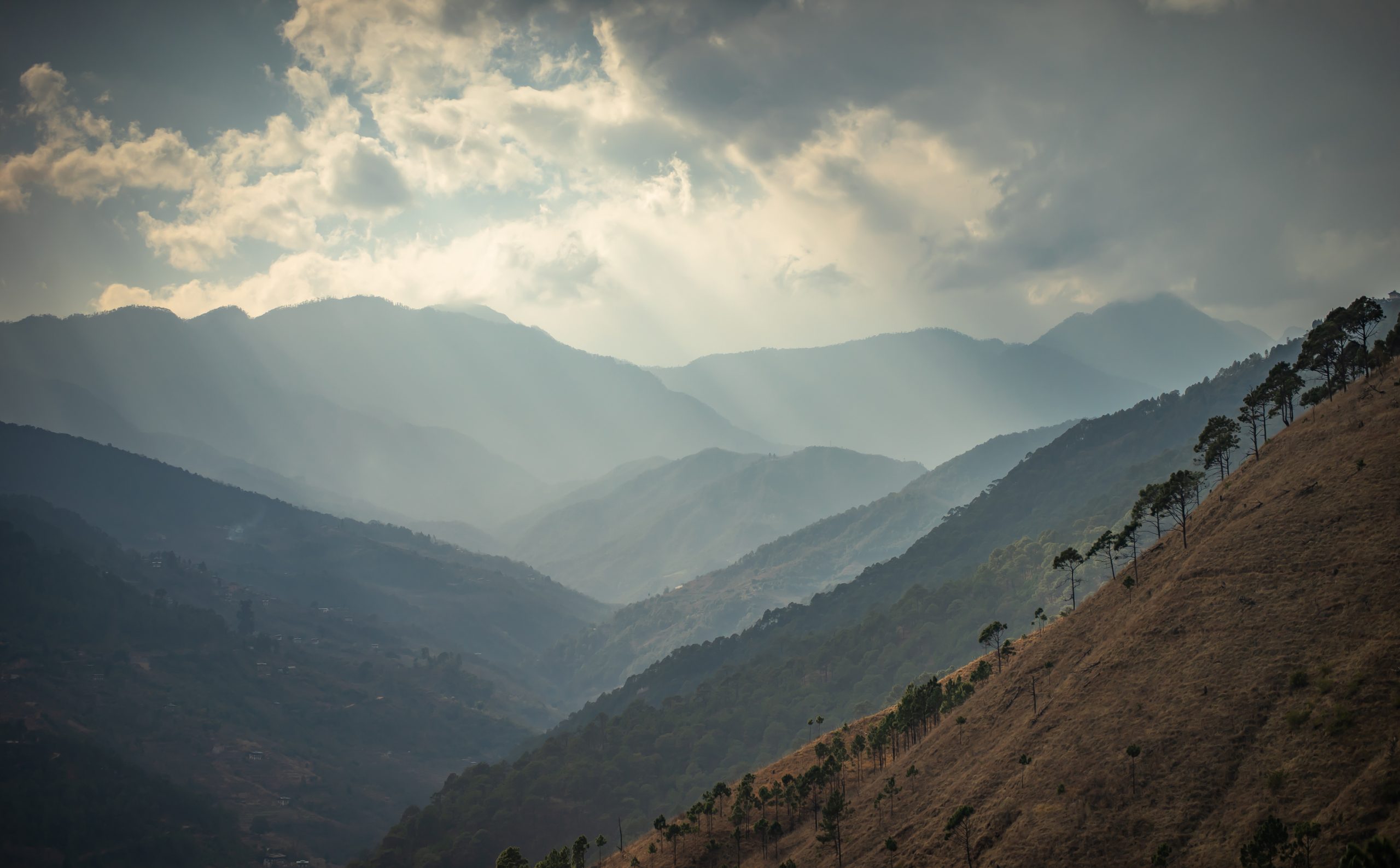 a mountain range with sun rays coming through the clouds