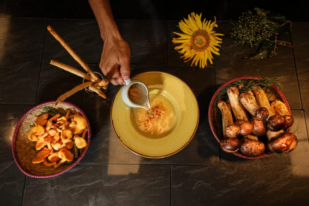 a person pouring soup into a bowl with mushrooms