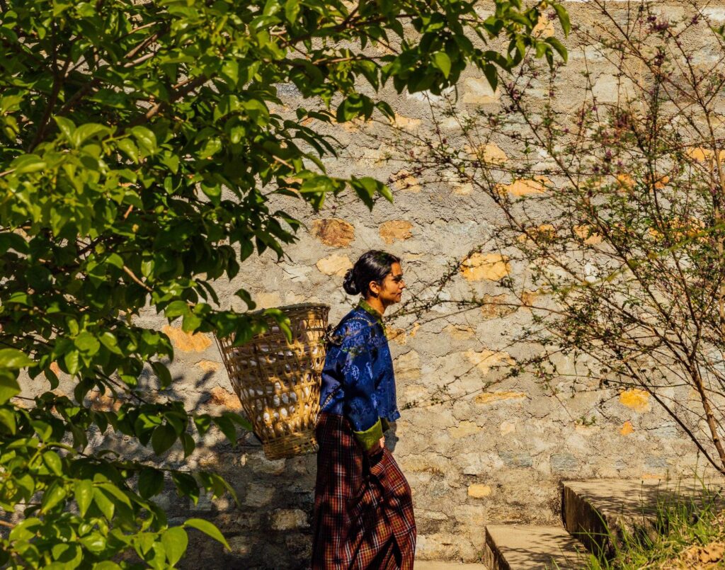 a woman walking down a path with a basket