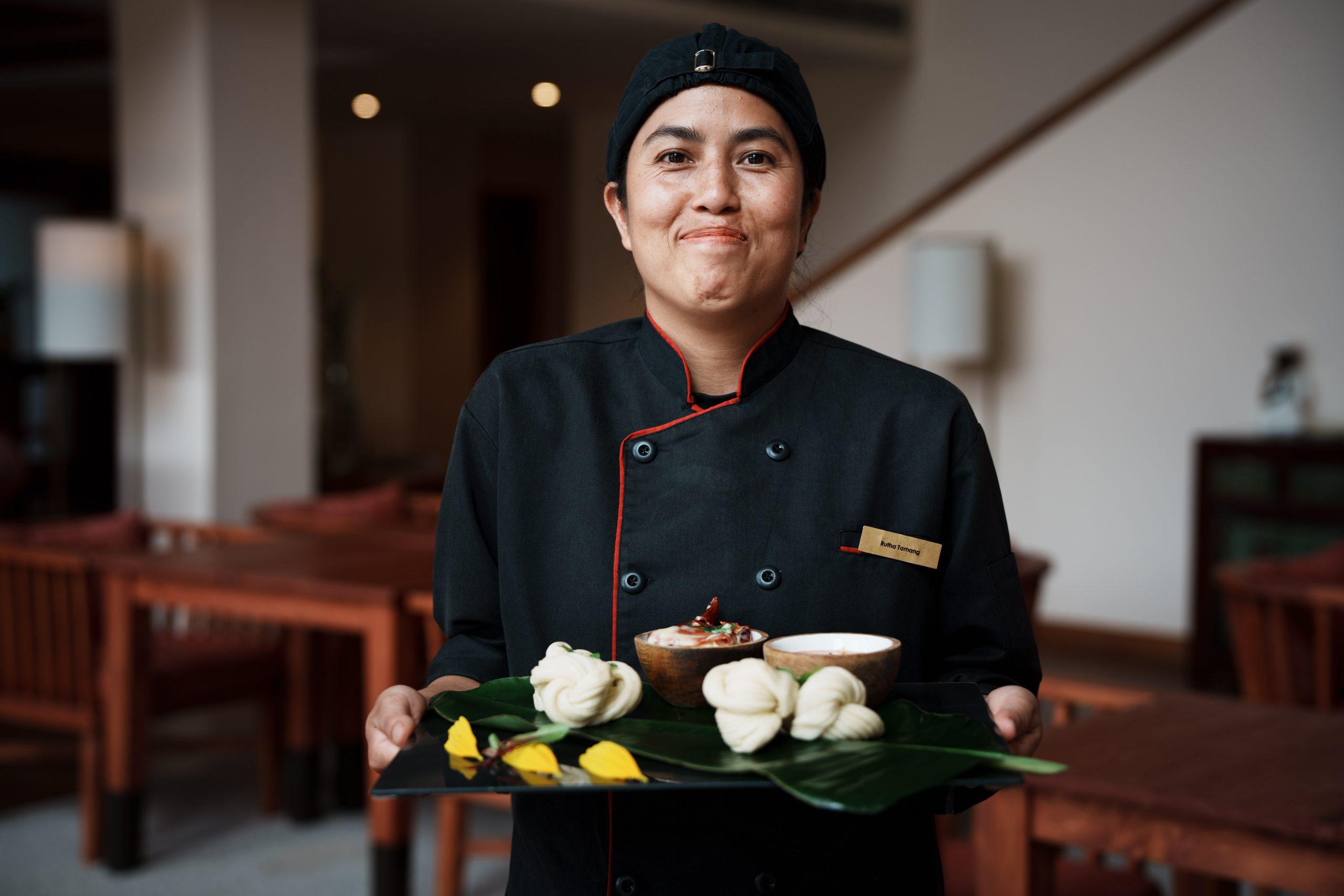 a woman wearing a chef uniform holding a tray of food