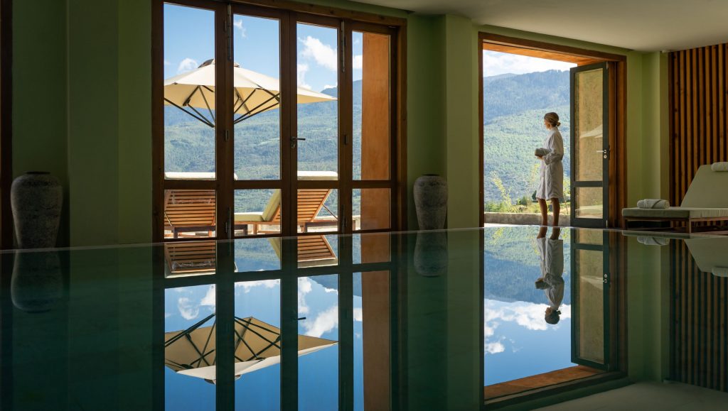 a woman standing in a room with a pool and a glass door