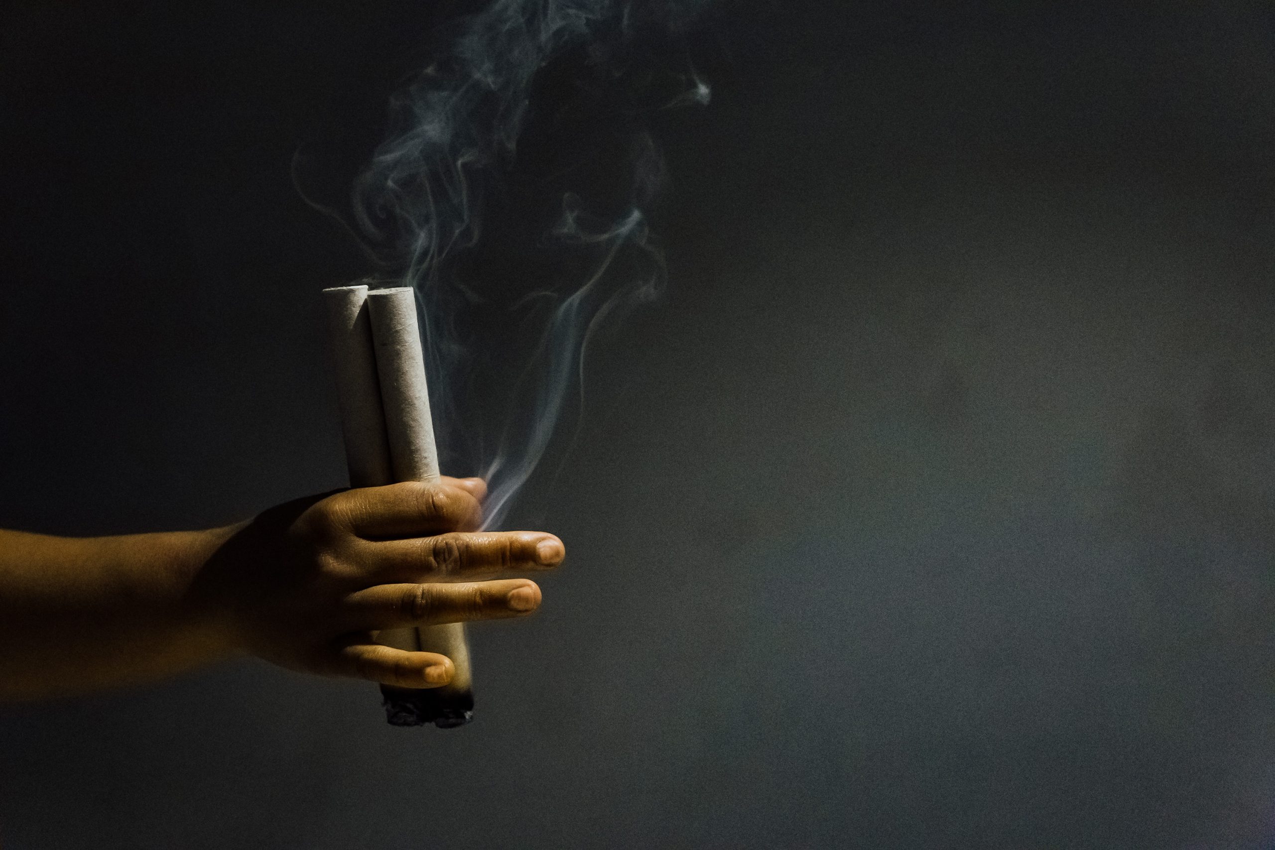 a hand holding a torch with smoke coming out